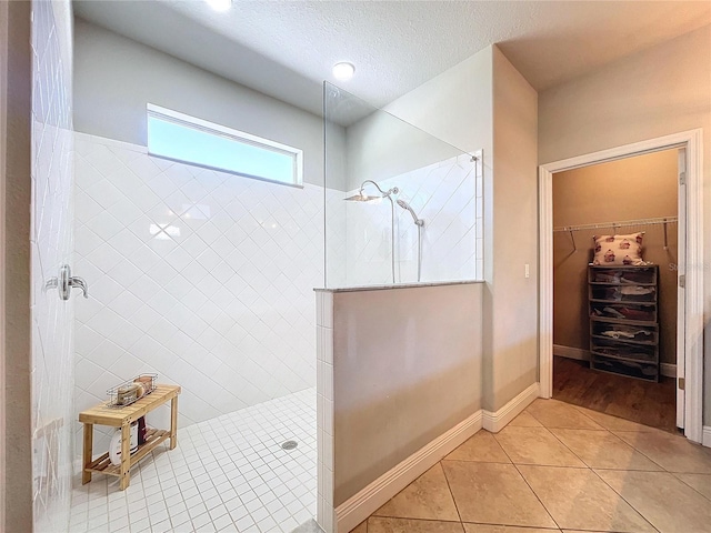 bathroom with a textured ceiling, tile patterned floors, and tiled shower