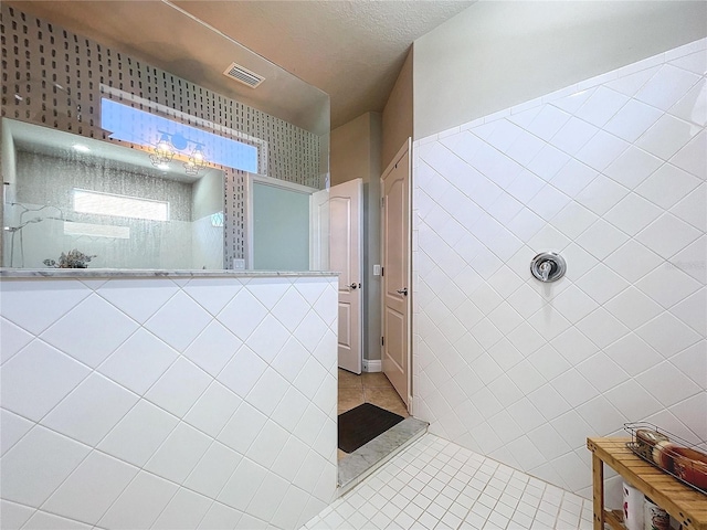 bathroom featuring tile patterned floors, a textured ceiling, and tile walls