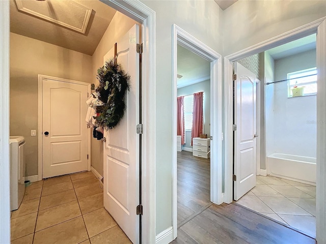 corridor with a wealth of natural light, vaulted ceiling, light hardwood / wood-style flooring, and separate washer and dryer