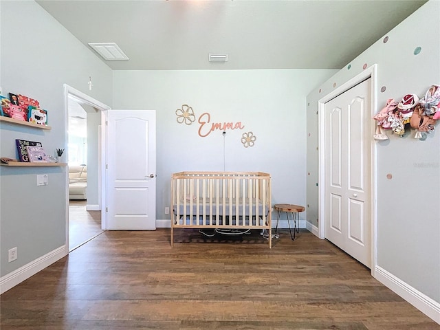 bedroom featuring dark hardwood / wood-style floors and a nursery area