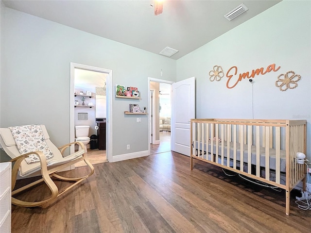 bedroom with a nursery area, wood-type flooring, and ceiling fan