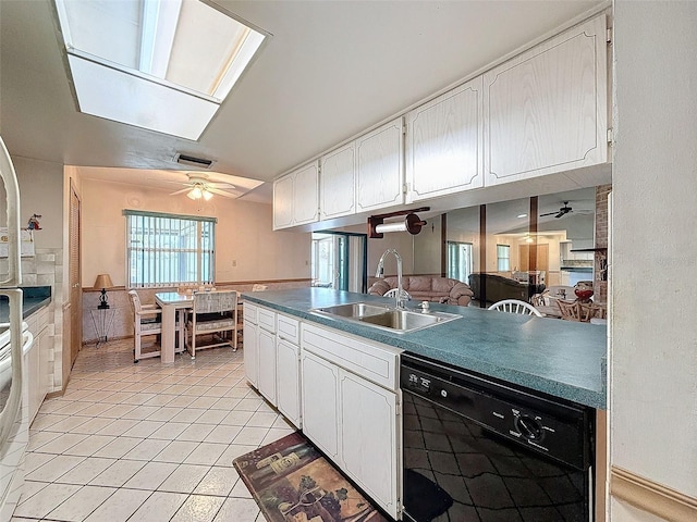 kitchen with black dishwasher, white cabinetry, light tile patterned flooring, a skylight, and sink