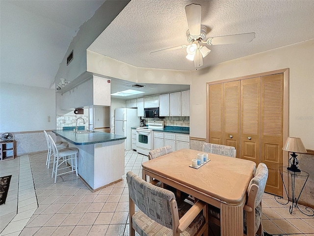 kitchen featuring white appliances, light tile patterned flooring, sink, kitchen peninsula, and white cabinetry