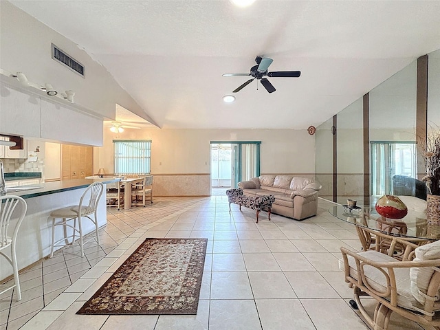 tiled living room with ceiling fan and vaulted ceiling