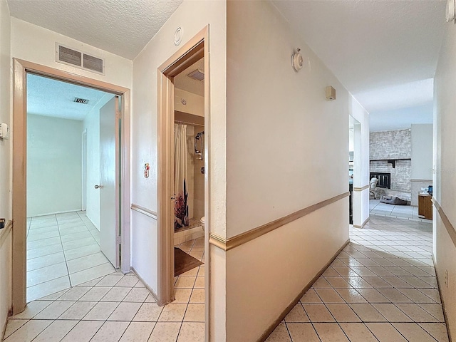 hallway with a textured ceiling and light tile patterned floors