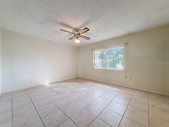 spare room with ceiling fan, a textured ceiling, and light tile patterned floors