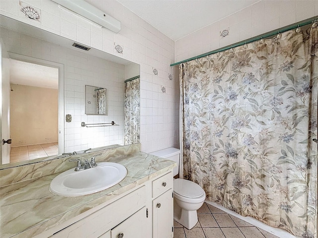 bathroom featuring tile walls, vanity, toilet, and tile patterned floors