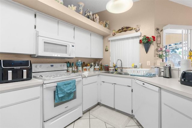 kitchen with white appliances, sink, lofted ceiling, white cabinets, and light tile patterned floors