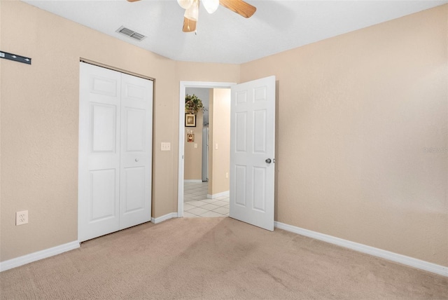 unfurnished bedroom with light carpet, a closet, and ceiling fan