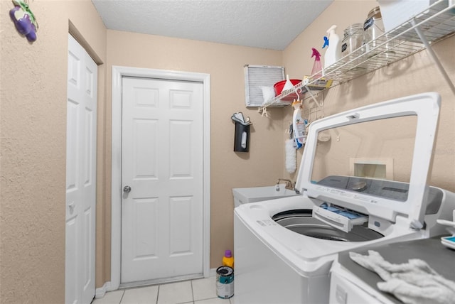 laundry area featuring a textured ceiling, sink, washer hookup, and light tile patterned floors