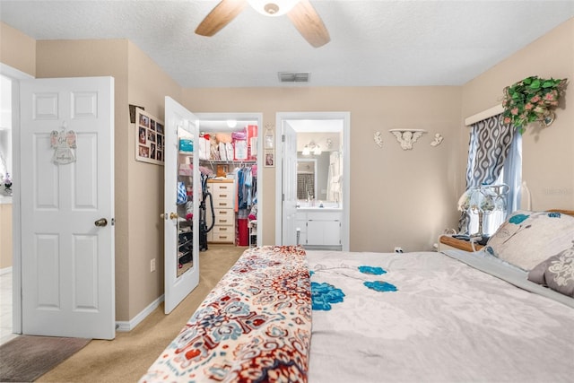 carpeted bedroom with a closet, a spacious closet, ensuite bathroom, a textured ceiling, and ceiling fan