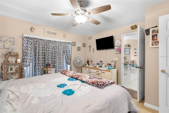 bedroom featuring a textured ceiling, light colored carpet, and ceiling fan