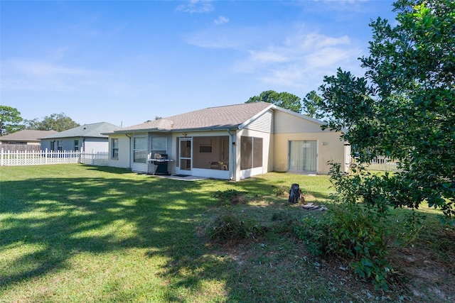 rear view of property featuring a yard and a sunroom