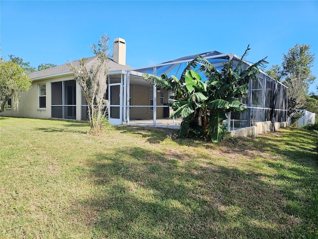 rear view of house with a lanai and a lawn