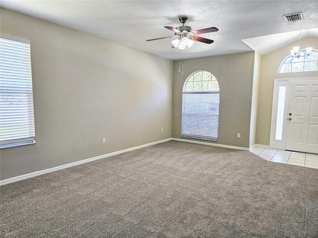 entryway featuring a textured ceiling, a wealth of natural light, light colored carpet, and vaulted ceiling