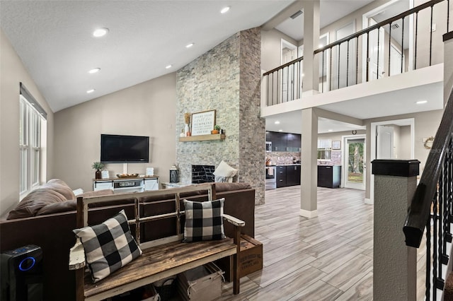 living room featuring hardwood / wood-style floors, a textured ceiling, a fireplace, and high vaulted ceiling