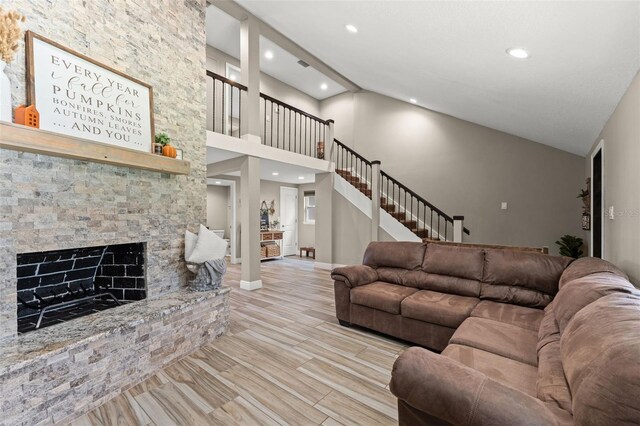 living room with light hardwood / wood-style floors, high vaulted ceiling, and a fireplace