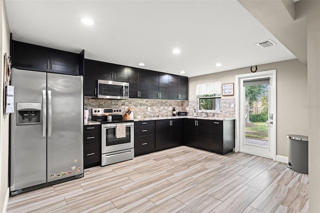 kitchen with appliances with stainless steel finishes, sink, light stone counters, and backsplash