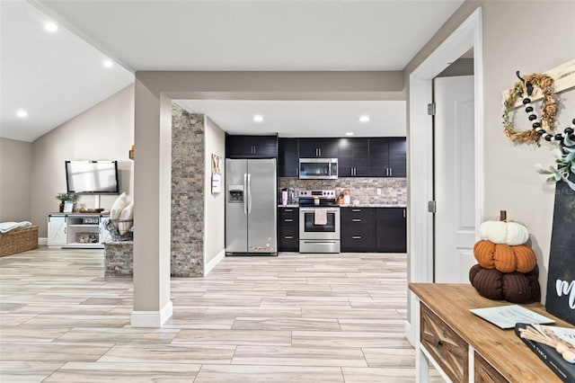 kitchen featuring appliances with stainless steel finishes, decorative backsplash, and vaulted ceiling