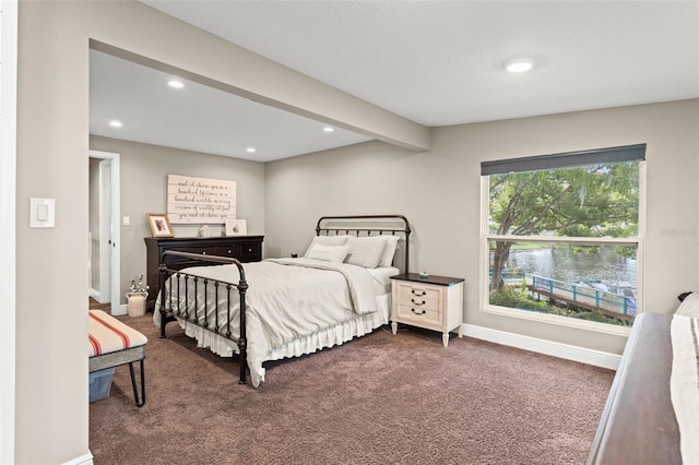 bedroom featuring dark carpet and beamed ceiling