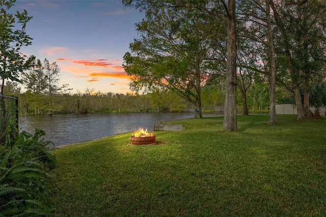 yard at dusk featuring an outdoor fire pit and a water view