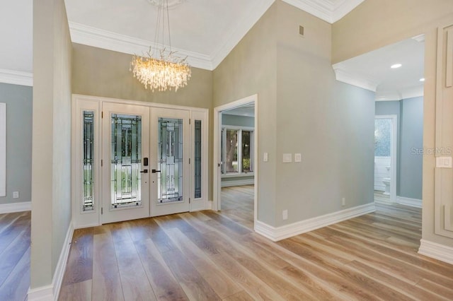 foyer with ornamental molding, french doors, and light hardwood / wood-style floors