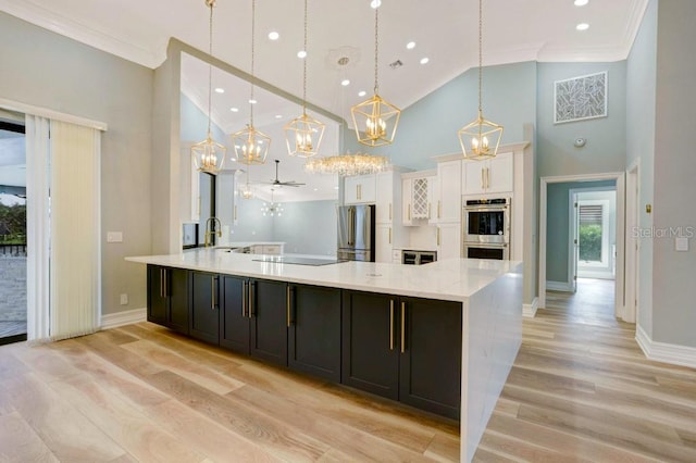 kitchen with light hardwood / wood-style flooring, appliances with stainless steel finishes, decorative light fixtures, and white cabinets