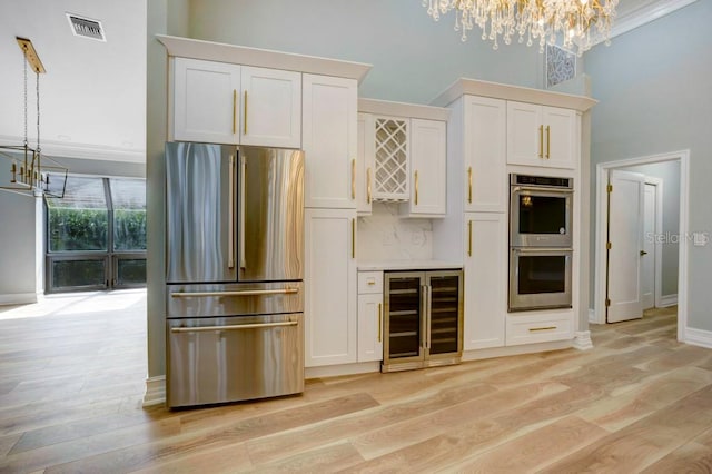 kitchen featuring stainless steel appliances, decorative light fixtures, light hardwood / wood-style flooring, and wine cooler