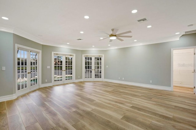 empty room with crown molding, french doors, ceiling fan, and light wood-type flooring