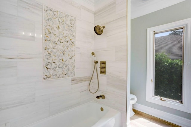 bathroom featuring hardwood / wood-style floors, tiled shower / bath, and toilet