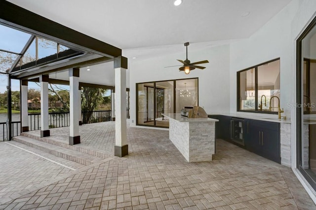 view of patio / terrace with glass enclosure, sink, and ceiling fan