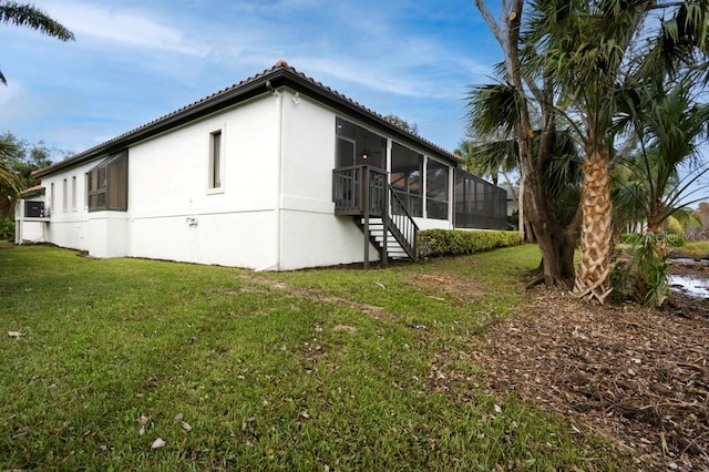 view of side of home with a lawn and a sunroom