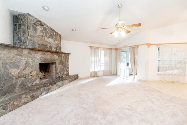 unfurnished living room featuring light carpet, a stone fireplace, lofted ceiling, and ceiling fan