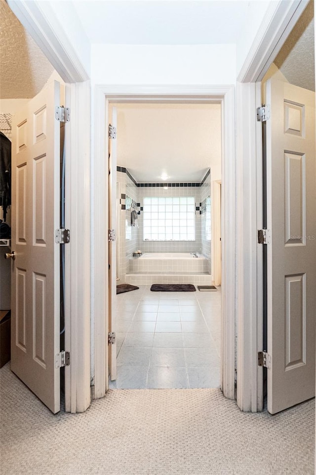 corridor featuring a textured ceiling and light tile patterned floors