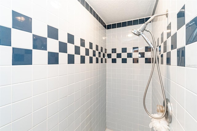 bathroom with a tile shower, a textured ceiling, and tile walls