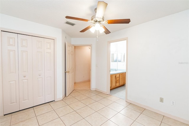 unfurnished bedroom featuring a closet, light tile patterned floors, connected bathroom, and ceiling fan