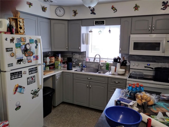 kitchen featuring gray cabinetry, sink, white appliances, and backsplash