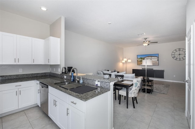 kitchen with kitchen peninsula, white cabinetry, dark stone counters, dishwasher, and sink