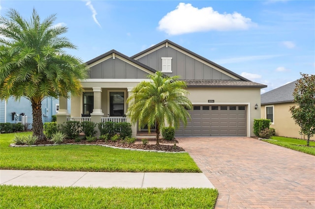 view of front of property featuring a garage, covered porch, and a front yard