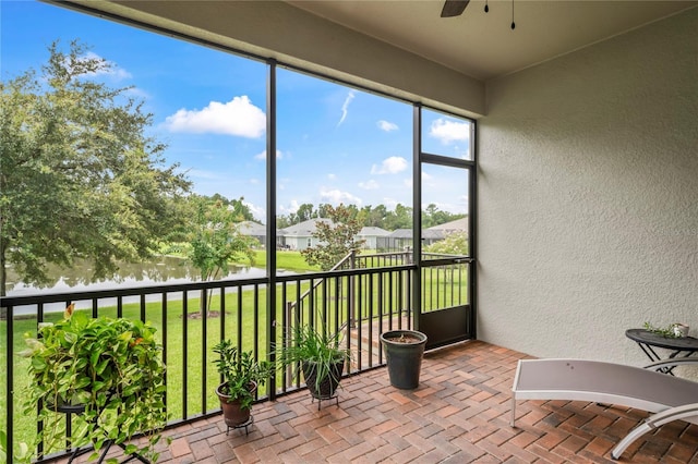 sunroom featuring a water view and ceiling fan