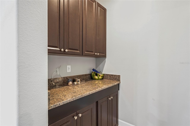 bar featuring dark brown cabinetry and dark stone countertops