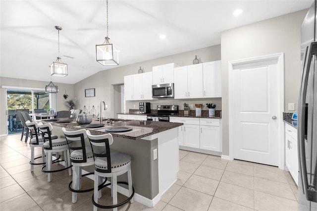 kitchen featuring a kitchen breakfast bar, an island with sink, stainless steel appliances, decorative light fixtures, and white cabinetry