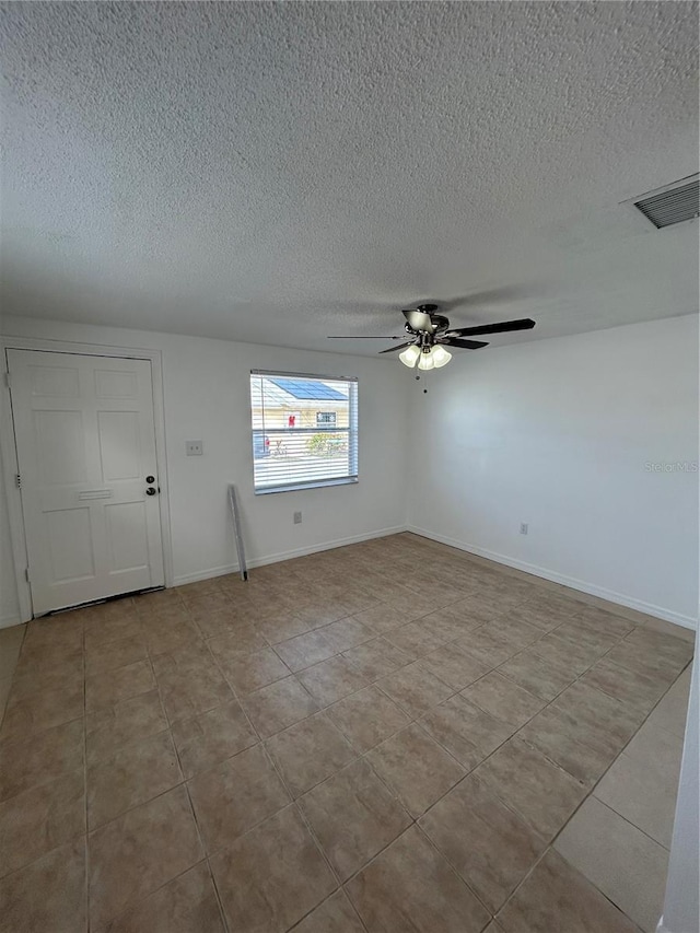 spare room featuring light tile patterned floors, a textured ceiling, and ceiling fan