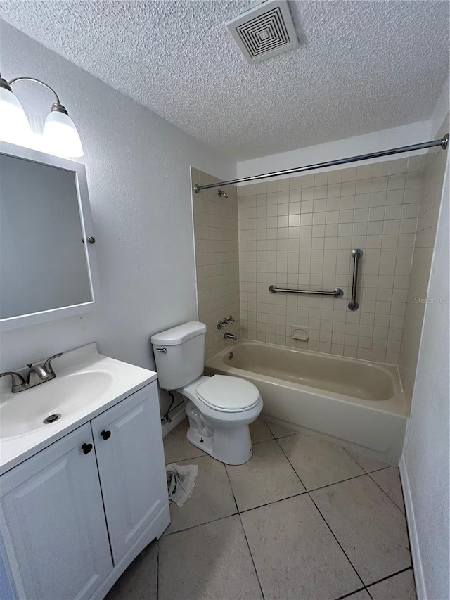 full bathroom with vanity, tile patterned floors, tiled shower / bath, toilet, and a textured ceiling