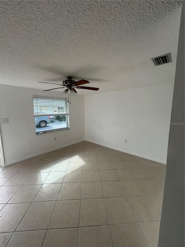 spare room with ceiling fan, light tile patterned flooring, and a textured ceiling