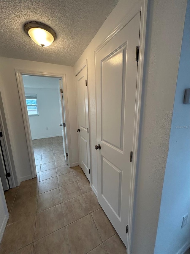 corridor featuring light tile patterned floors and a textured ceiling