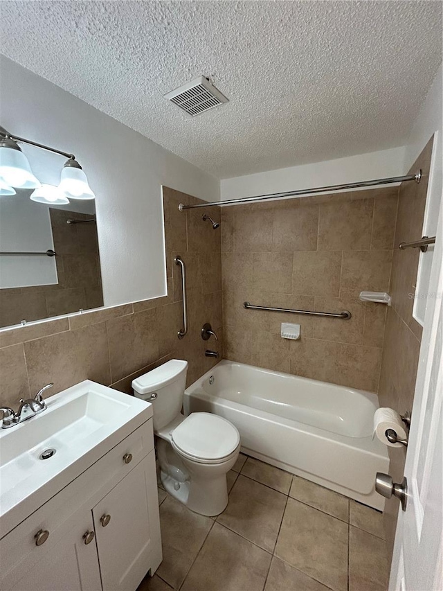 full bathroom with tiled shower / bath combo, tile patterned flooring, toilet, vanity, and tile walls