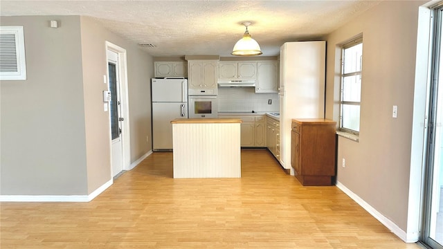 kitchen featuring pendant lighting, tasteful backsplash, a center island, light hardwood / wood-style floors, and white appliances