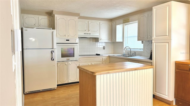 kitchen featuring sink, white appliances, a center island, light hardwood / wood-style floors, and decorative backsplash