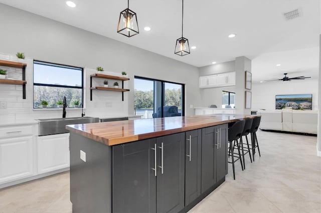 kitchen with wooden counters, white cabinets, and hanging light fixtures